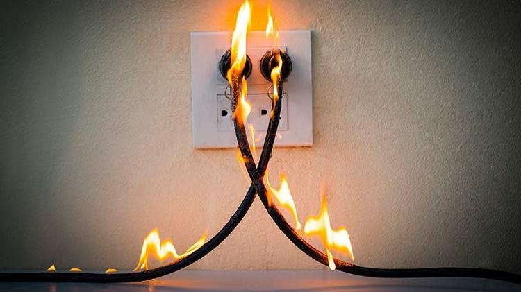 Electrical cords plugged into the wall are on fire due to an arc flash.